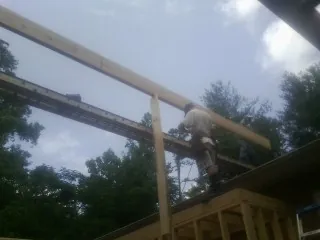 Carpenter setting a ridge beam over a new addition frame — Ice Dam Removal by Roofing Brothers in Bondsville