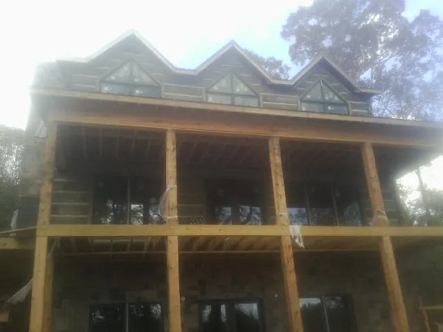 Dormers and porch framing on a large log home under construction — Roof Coating work by our crew in Bondsville