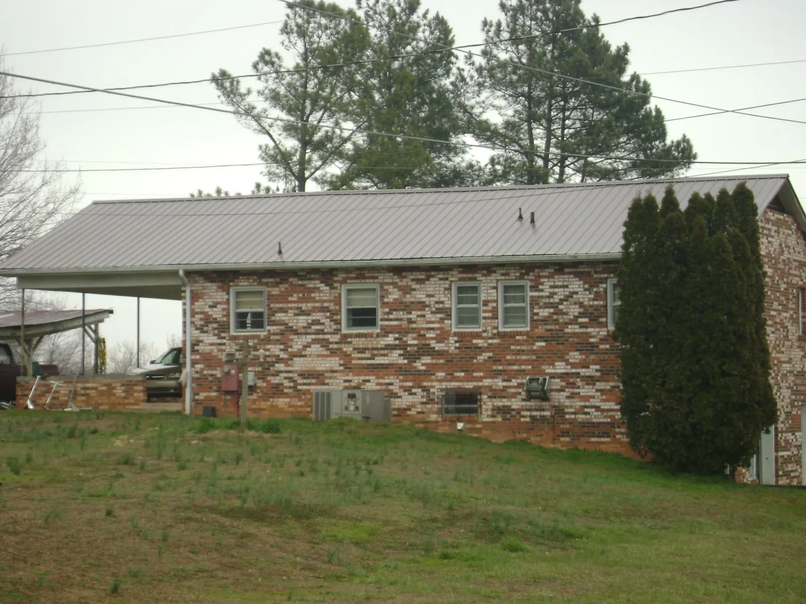 Gray metal roof on a brick split level home with a carport in Bondsville