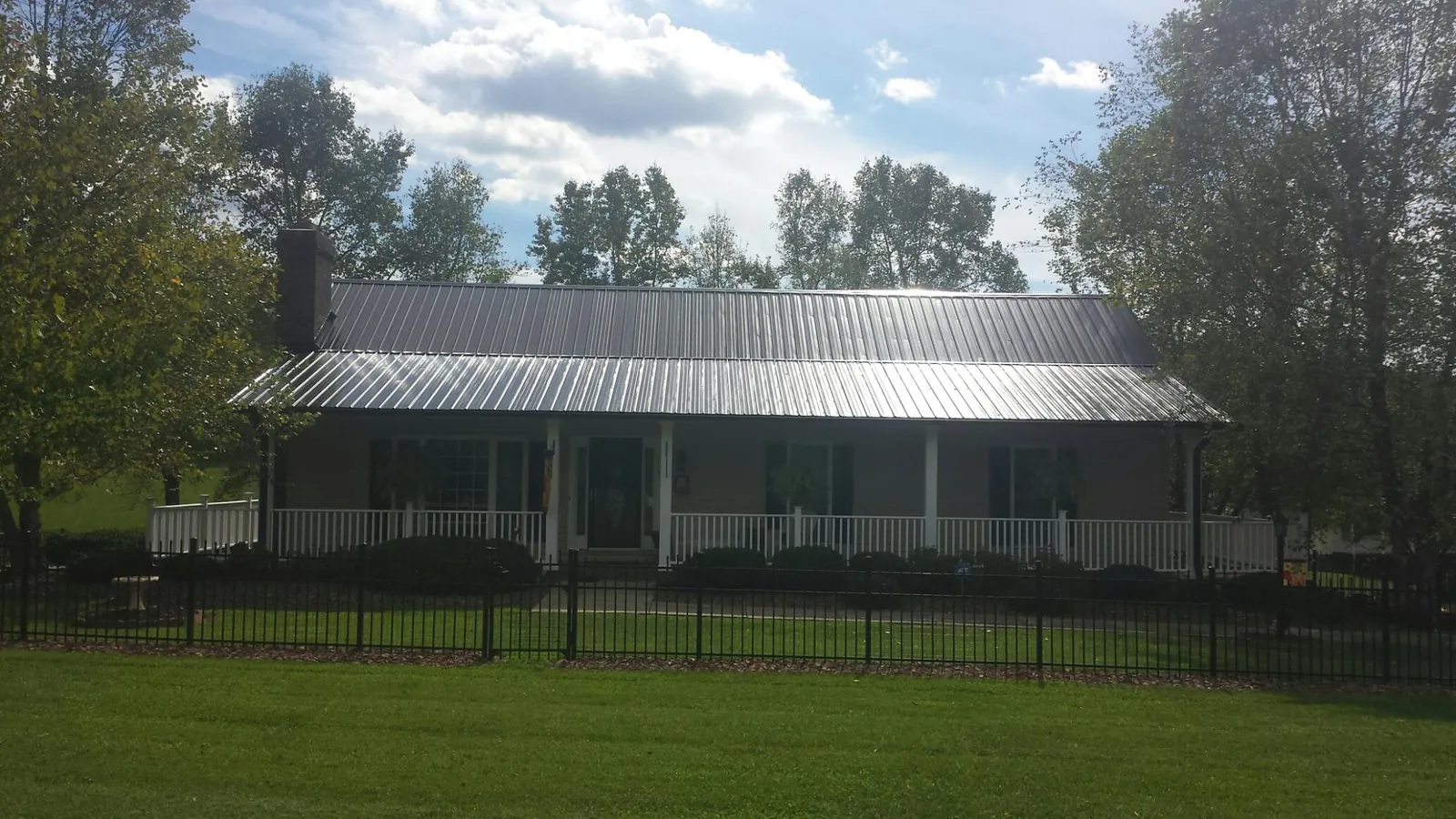 Gray metal roof on a brick ranch with a full width front porch — Gutter Guard Installation work by our crew in Bondsville