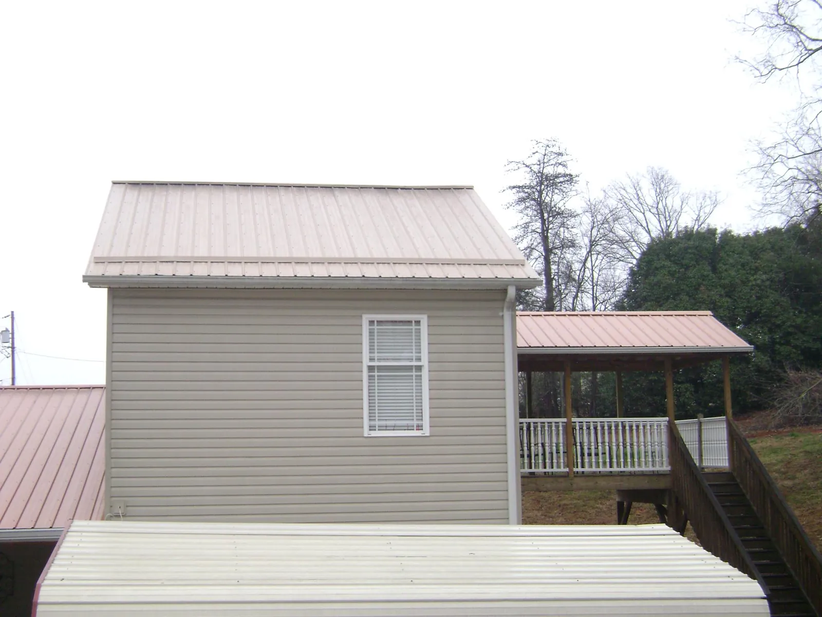 Tan metal roofs on a two story addition and attached porch, from a Roof Replacement job in Bondsville