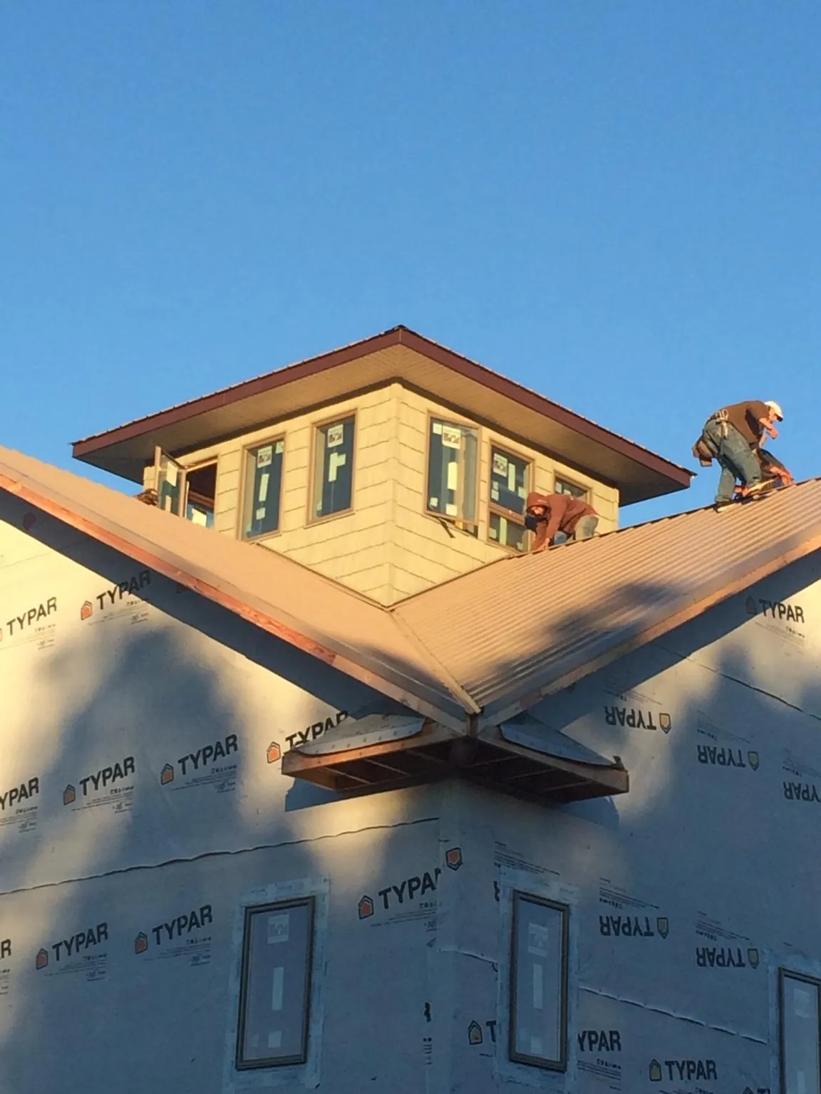 Roofers working around a rooftop cupola on a new metal roof at sunset — Roof Waterproofing in Bondsville by Roofing Brothers